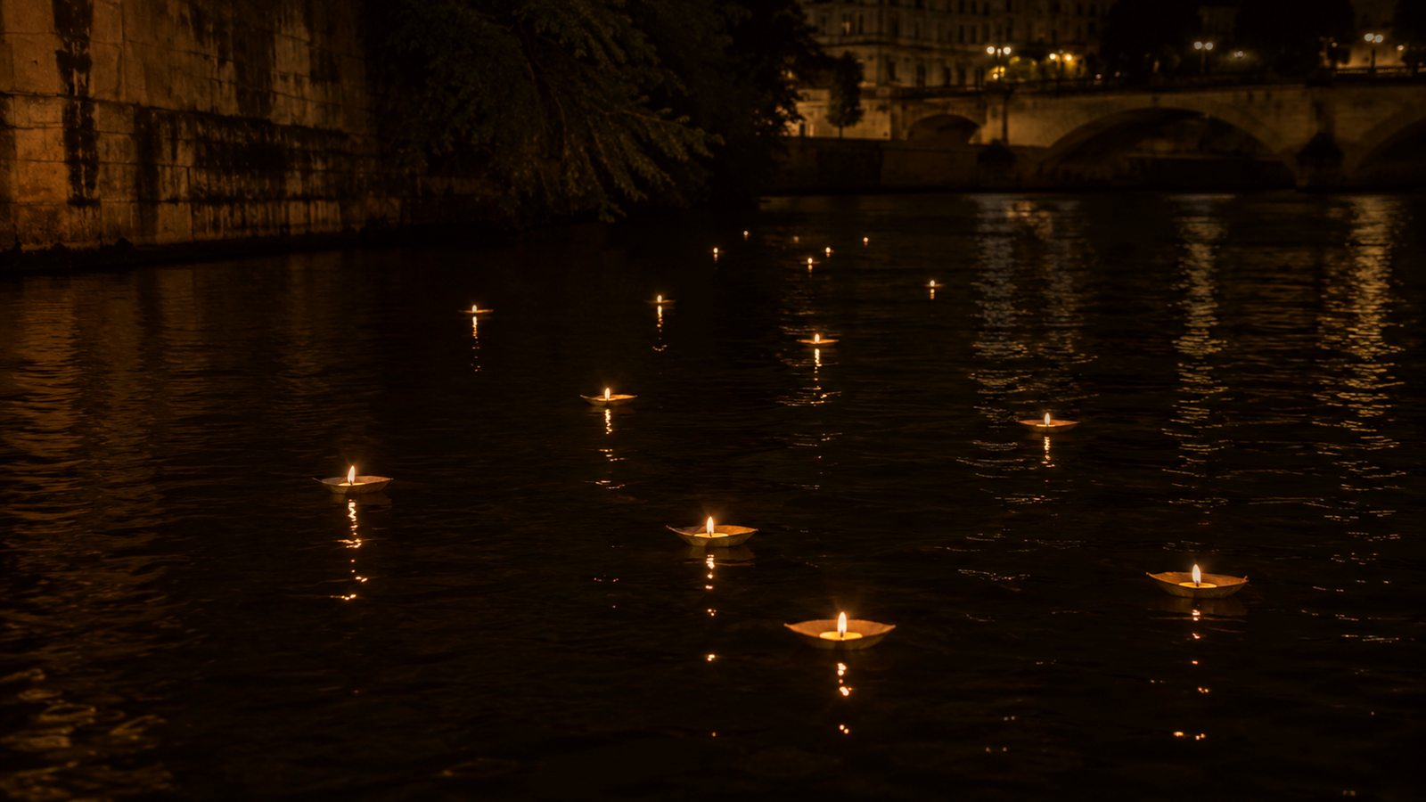Small paper boats, each carrying a lit candle, set adrift on the dark water of the Seine at night, with the stone quay and a bridge of Paris beyond.